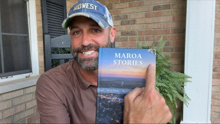 Mike Pope holding Maroa Stories on his porch