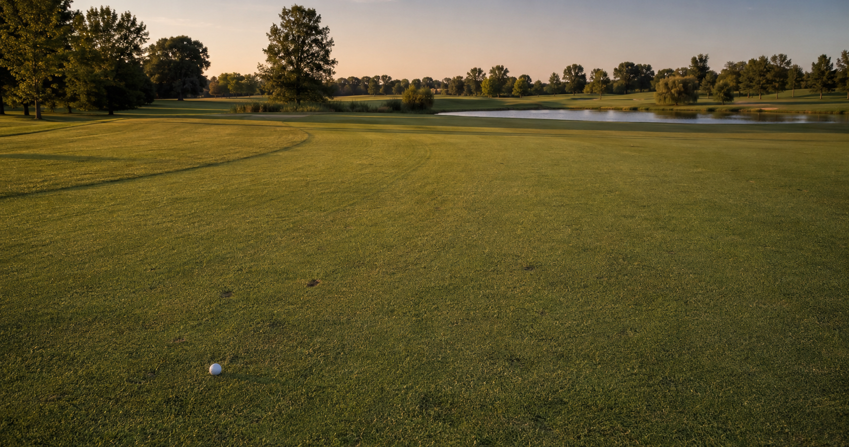 A lone golf ball resting far short of a distant green on a quiet public golf course